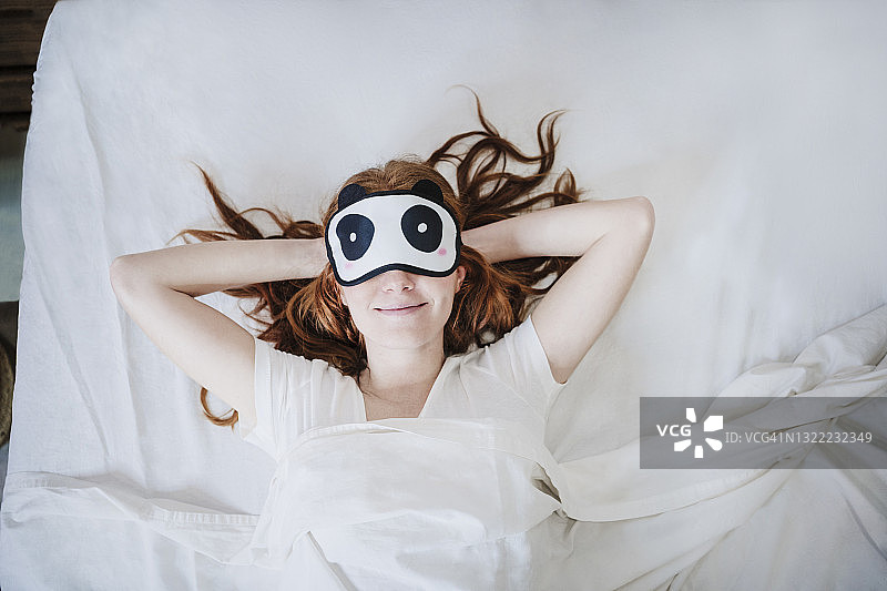 放松的女人双手枕在脑后在床上睡觉图片素材