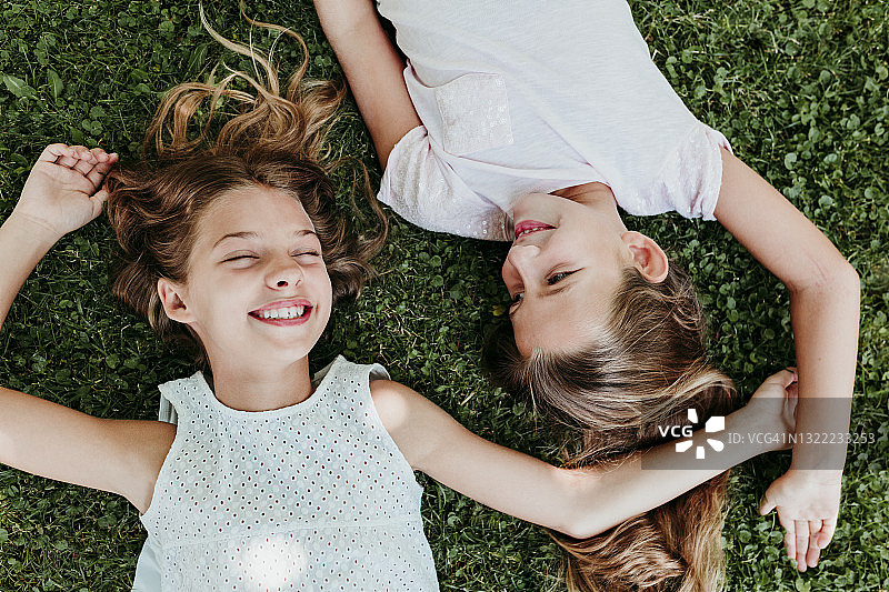 快乐的女孩们在夏天躺在草地上图片素材