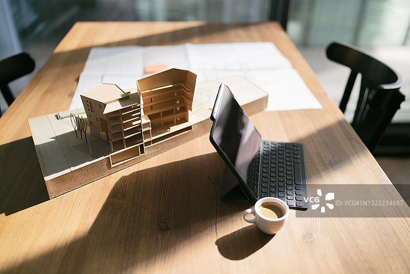 办公室桌子上放着带有咖啡杯和建筑模型的笔记本电脑图片素材