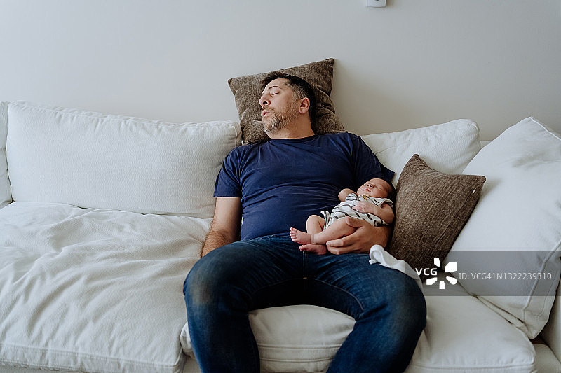 疲惫的父亲与男婴在客厅的真实瞬间图片素材