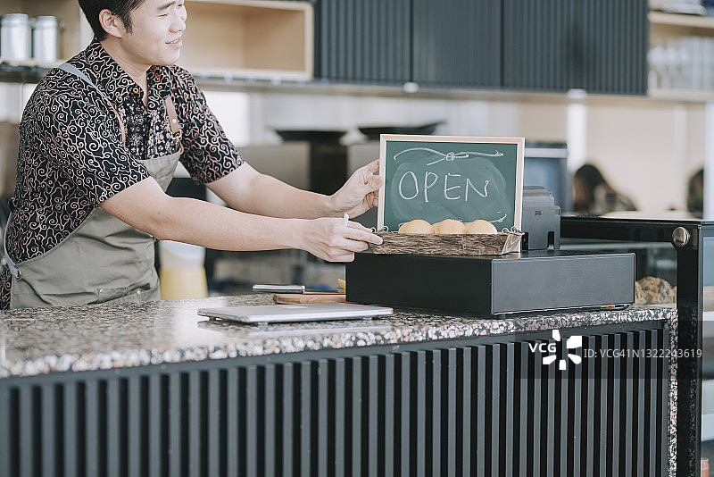 华人男性咖啡店老板早上用粉笔写“营业中”图片素材