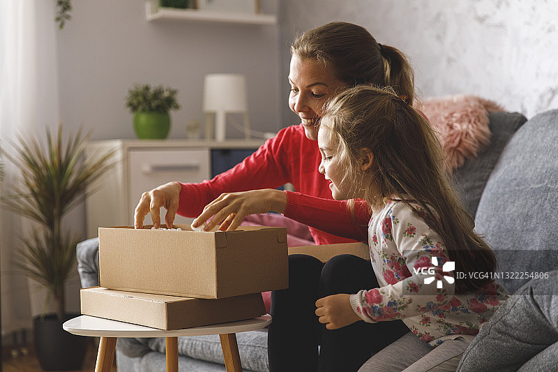 小女孩和妈妈一起打开包裹，非常兴奋图片素材