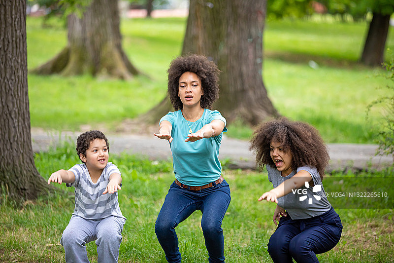 一位非裔美国妇女在病毒期间与她的孩子在公园里慢跑热身图片素材