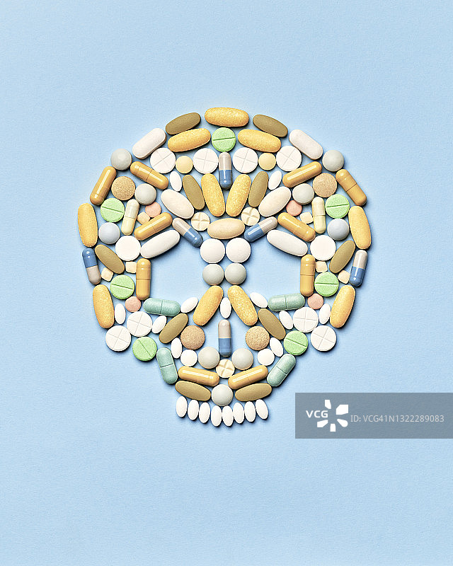 蓝色背景上排列成人类头骨形状的药丸图片素材