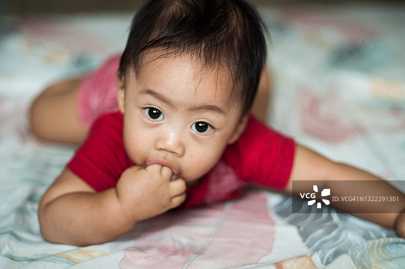 东南亚男婴趴在床上吮吸手指图片素材