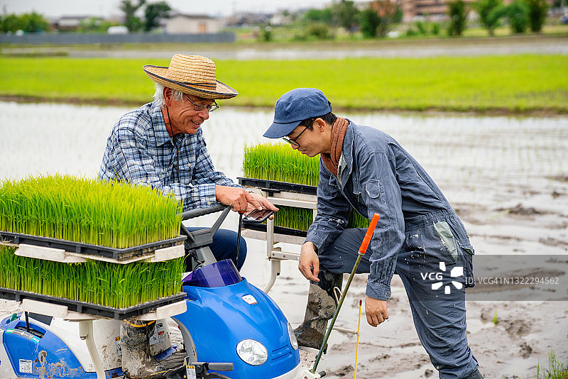 年长的农民用智能手机与另一位农民分享信息图片素材