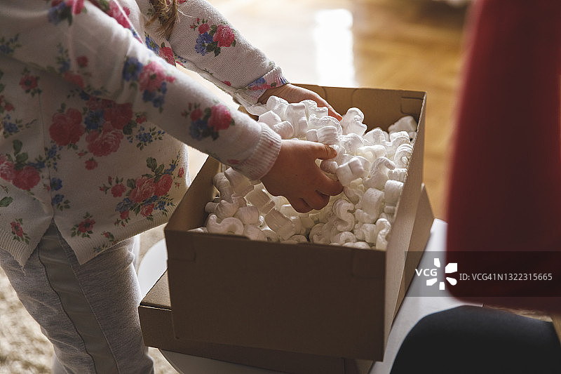 小女孩玩弄妈妈包裹里的填充物图片素材