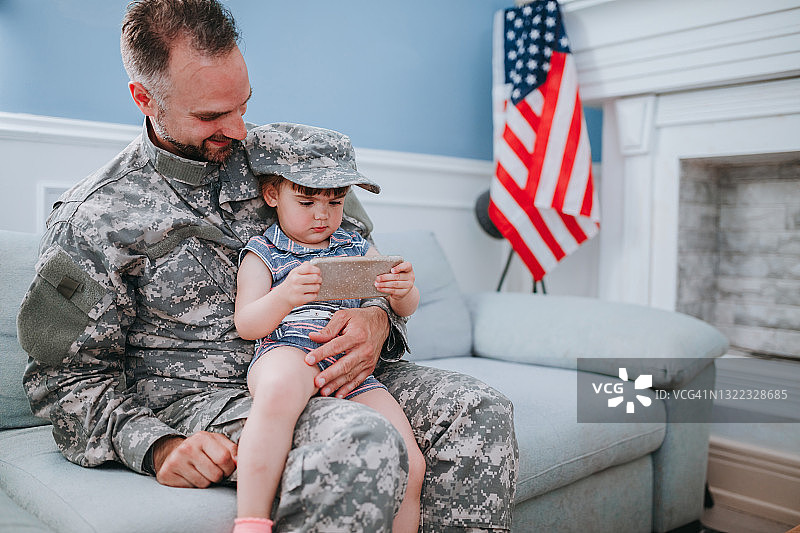 快乐的军人父亲和女儿一起使用手机图片素材