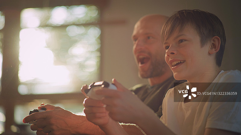 疫情期间的屏幕时间：父子玩电子游戏侧面照图片素材