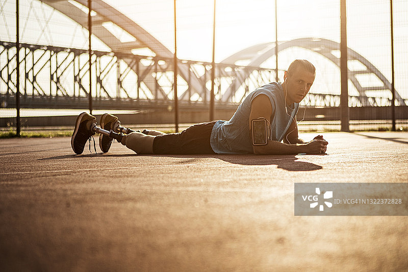 残疾青年在运动场上做俯卧撑，休息一下图片素材