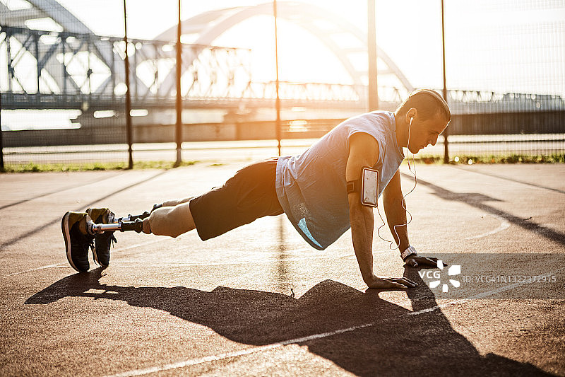 在阳光下做俯卧撑的年轻残疾男子图片素材