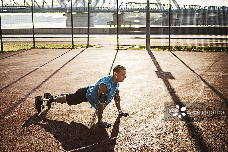 残疾青年在运动场上做俯卧撑图片素材