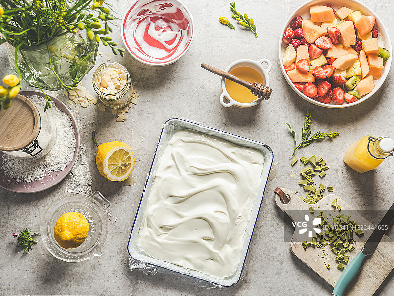 浅灰色厨房桌上的方形碗装酸奶与水果蜂蜜杏仁巧克力图片素材