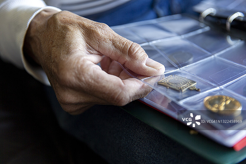 英国，东苏塞克斯，年长男子手握硬币相册的特写图片素材