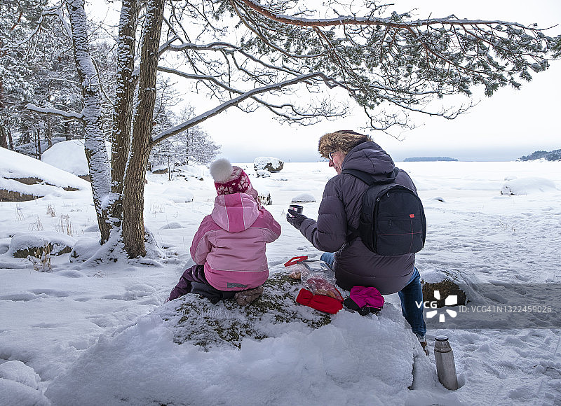 父亲和宝宝在海湾野餐。一家人喝着热茶，享受着交谈和大自然图片素材