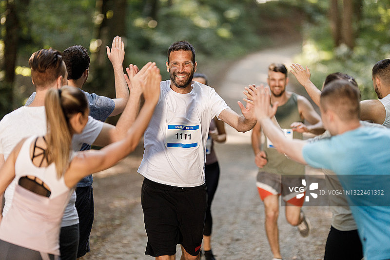 快乐的马拉松运动员在终点线迎接运动员图片素材