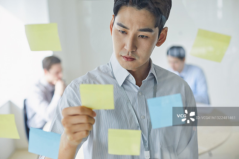 看着便利贴的亚洲商务男士图片素材