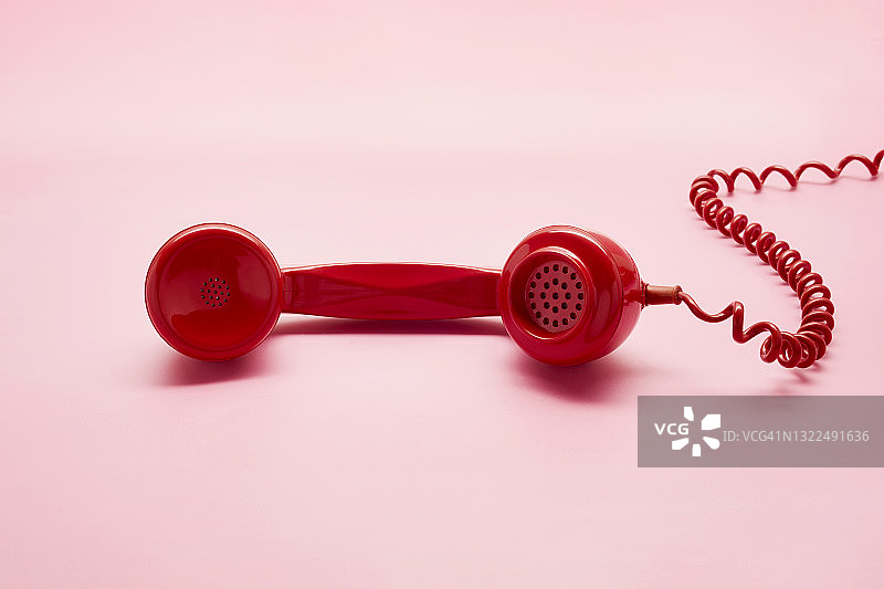 粉色背景上的红色老式电话听筒图片素材