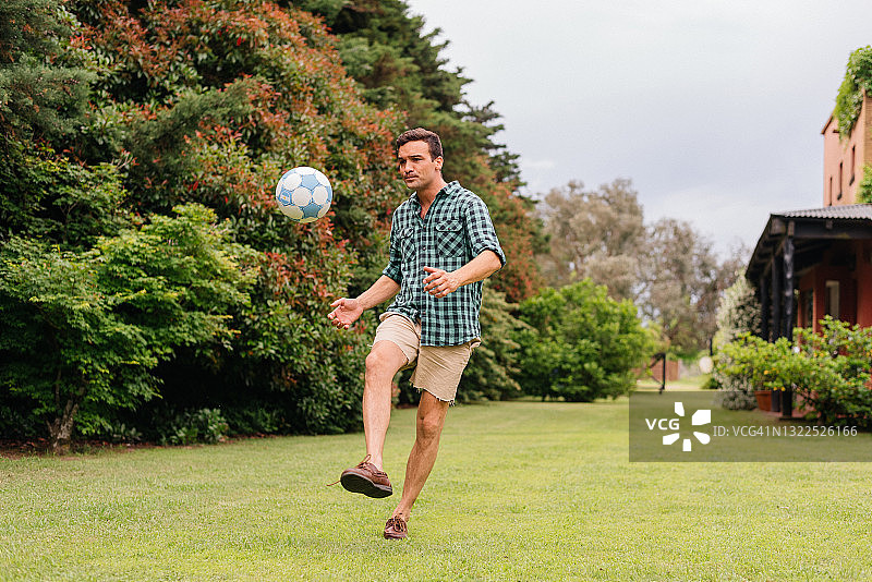 男人在后院草坪上踢足球图片素材