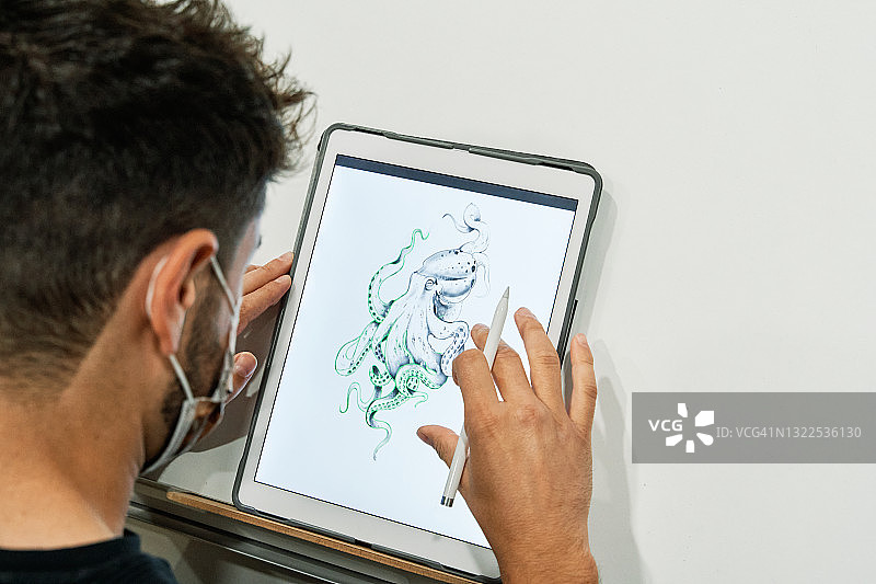 戴口罩的纹身师在平板电脑上设计纹身图片素材