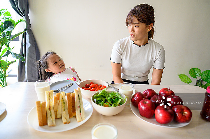 快乐的亚洲家庭，母亲和女儿在厨房里享受健康的早餐时光图片素材
