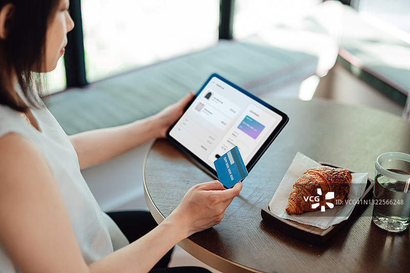 使用平板电脑进行网购的年轻女人正在用信用卡支付图片素材