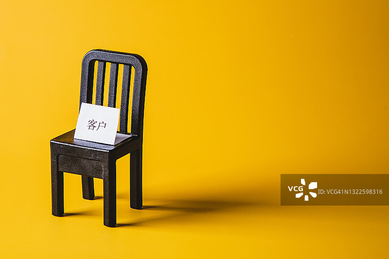黄色背景上的带“客户”标志的空椅子图片素材