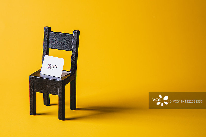 黄色背景上的带有“客户”标志的空椅子图片素材