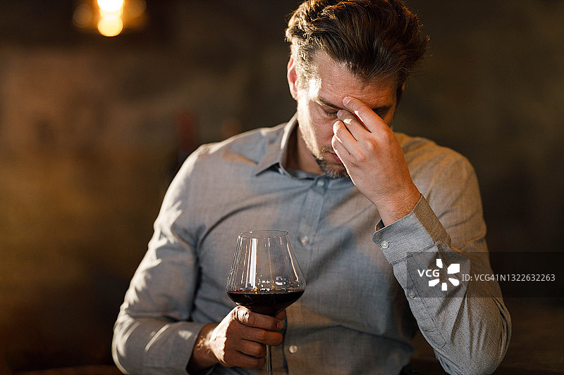 商人酒吧饮红酒时头痛图片素材