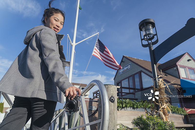 手持相机在纽波特港口观光的中年魅力女性图片素材