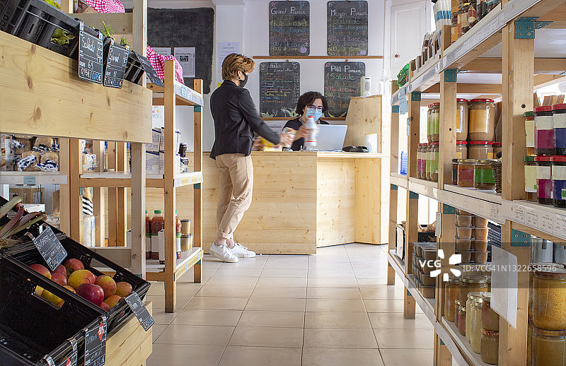 在社区互助杂货店的柜台前，一位顾客和一位收银员图片素材