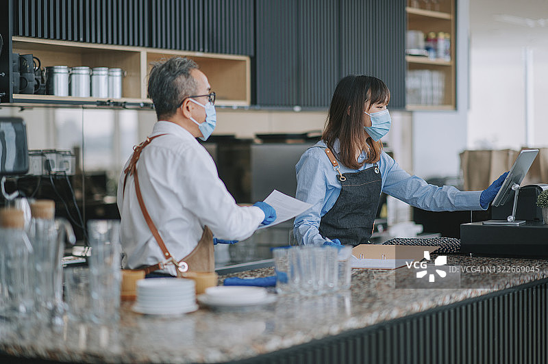 亚洲华人自助餐厅工作的资深男人在厨房柜台与他的女同事沟通指导图片素材