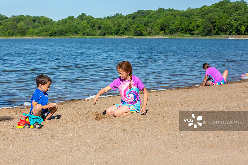 三个孩子在夏日海滩上玩耍图片素材