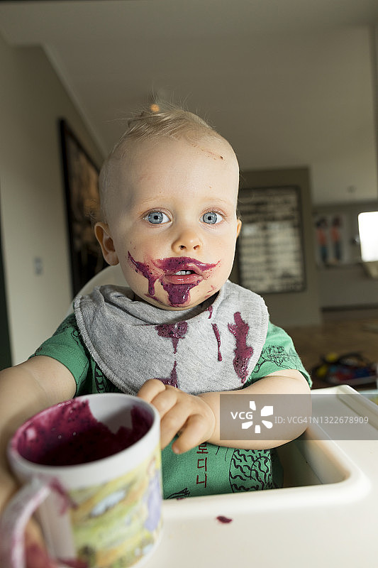 正在吃浆果冰沙的脏兮兮的男婴图片素材