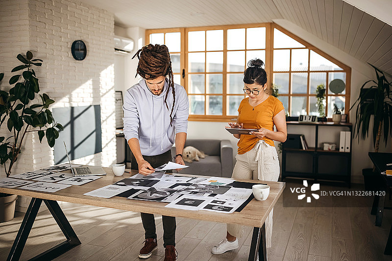 在办公室讨论照片的年轻平面设计师图片素材