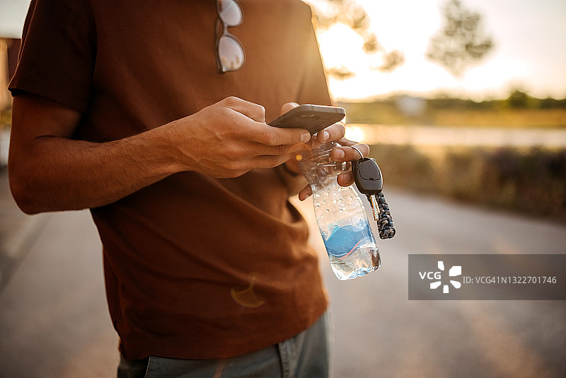 拿着水、钥匙和手机的成年男子图片素材