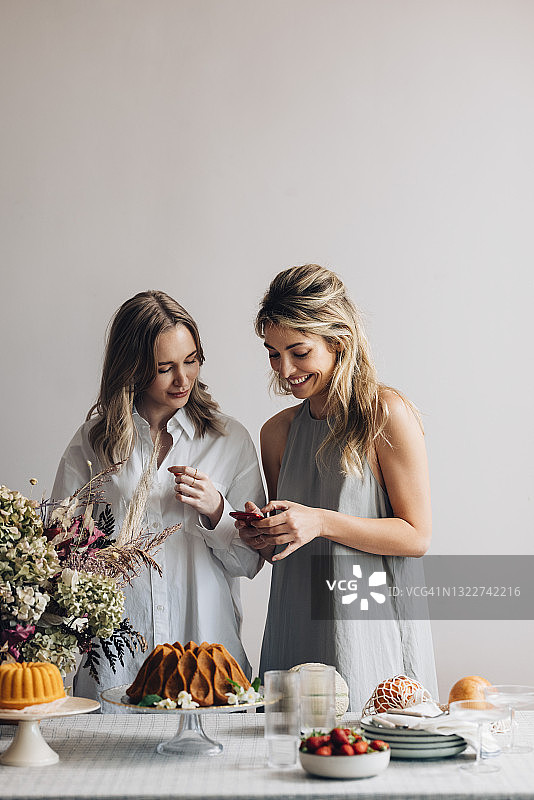 两位金发女子在生日派对上用手机刷社交媒体图片素材