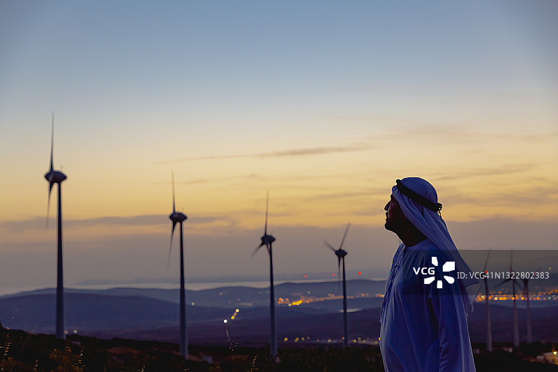 风力涡轮机旁的自信阿拉伯商人肖像图片素材