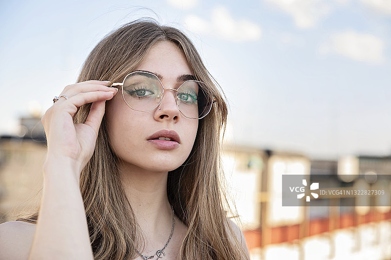 戴眼镜的美丽少女站在露台看向镜头图片素材