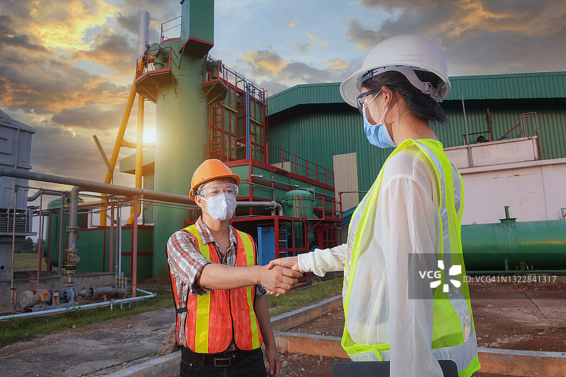 两名工程师在泰国一家工厂前握手图片素材