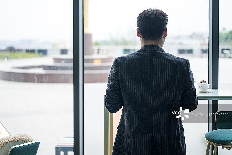 背对落地窗的商务男士图片素材