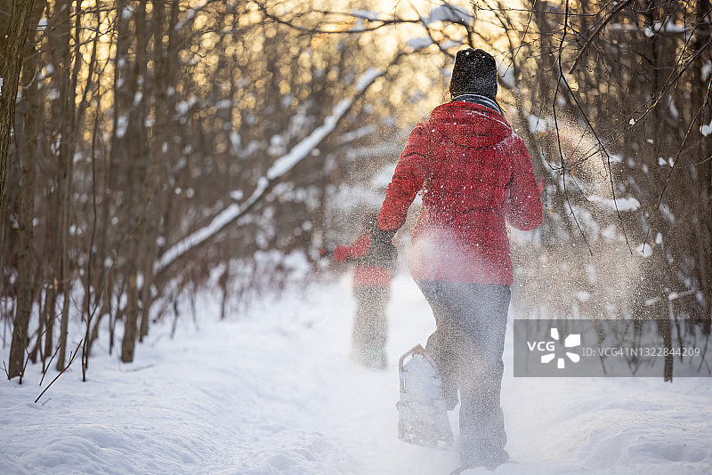 妈妈和儿子冬日雪地日落时穿雪鞋跑步图片素材