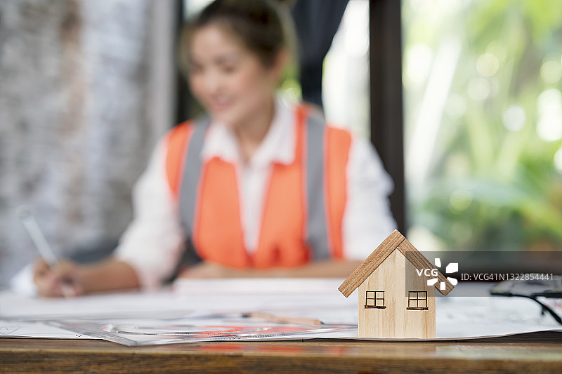 建筑办公室的办公桌，有房屋、建筑模型和设计师在后台工作图片素材