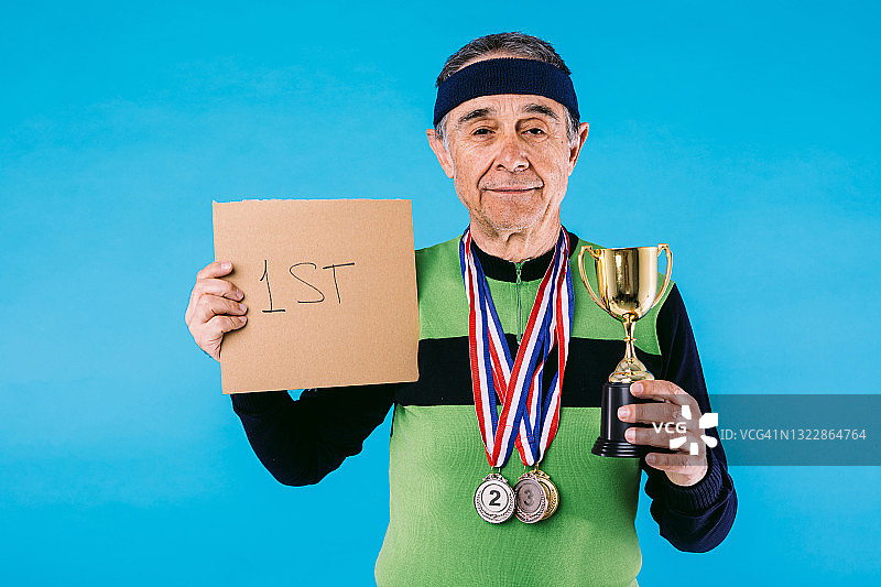 身穿复古球衣、佩戴奖牌、手持奖杯的老年运动员图片素材