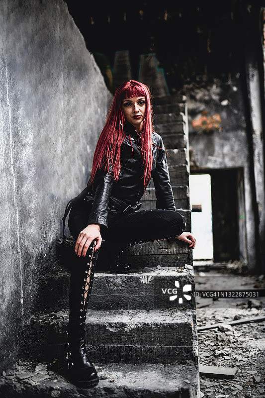 坐在建筑物废墟楼梯上的美丽哥特风女子图片素材