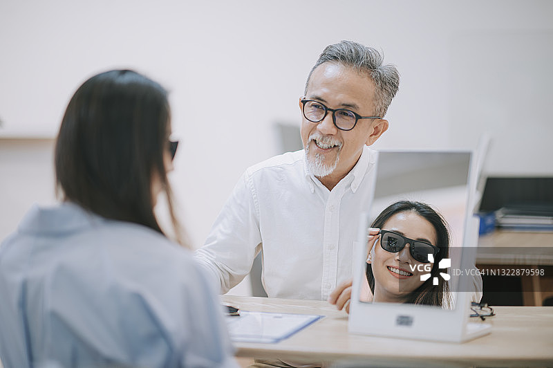中国年长的男店员在眼镜店向女顾客讲解图片素材