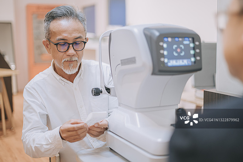 中国老年男人在眼科医生办公室做完眼科检查后，正在阅读他的视力测试结果图片素材