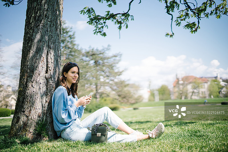 在阳光明媚的城市公园里放松的年轻女子图片素材