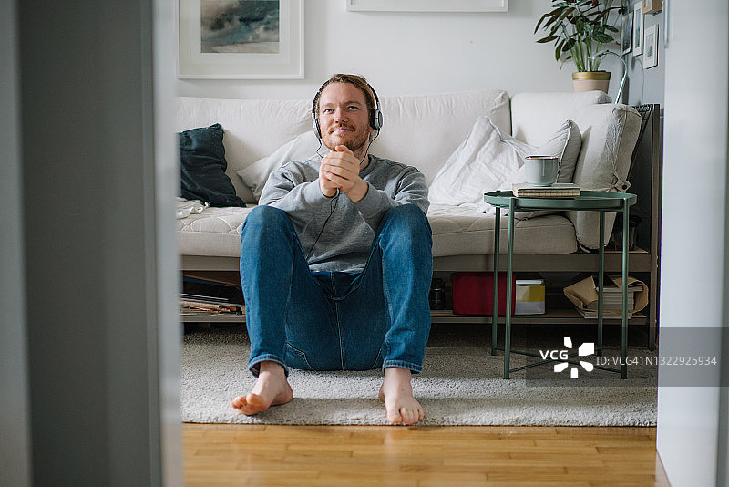 年轻男人在家戴耳机听音乐图片素材