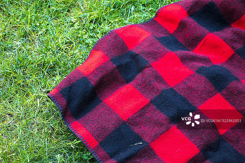草地上传统的红黑格子羊毛野餐毯图片素材